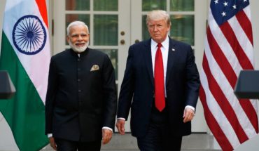 Smiling Narendra Modi And Donald Trump Standing In The Background Of Indian & USA Flags.