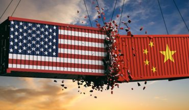 USA And Chinese Flags Crashed Containers On Sky At Sunset Background Representing The Trade War.